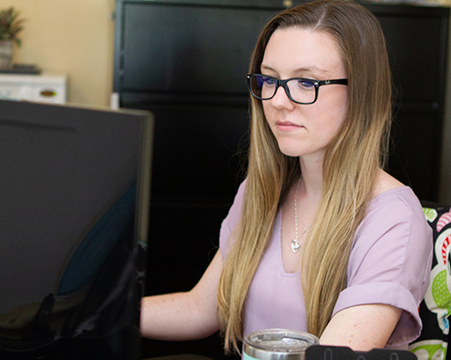 A young woman is reading on her computer
